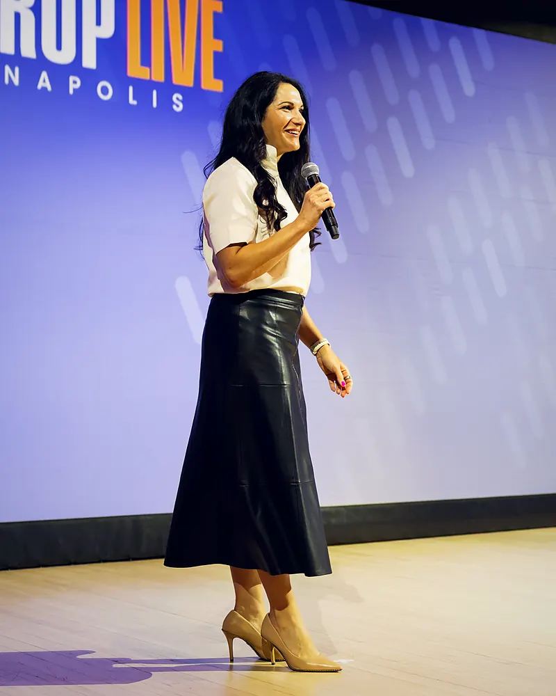 Me walking across a big stage with a microphone, shown full length